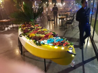 קיאק צהוב מואר עמוס בפירות חתוכים ומסודרים באולם אירועים
