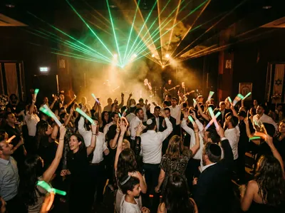 קרני לייזר ירוקות וענבר נפרשות מעל רחבת ריקודים מלאה